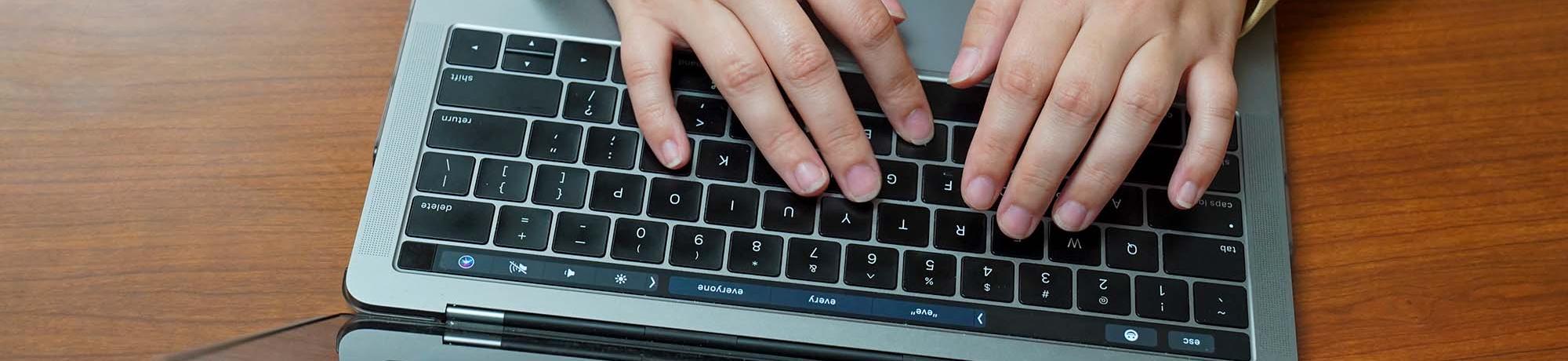 hands typing on laptop keyboard